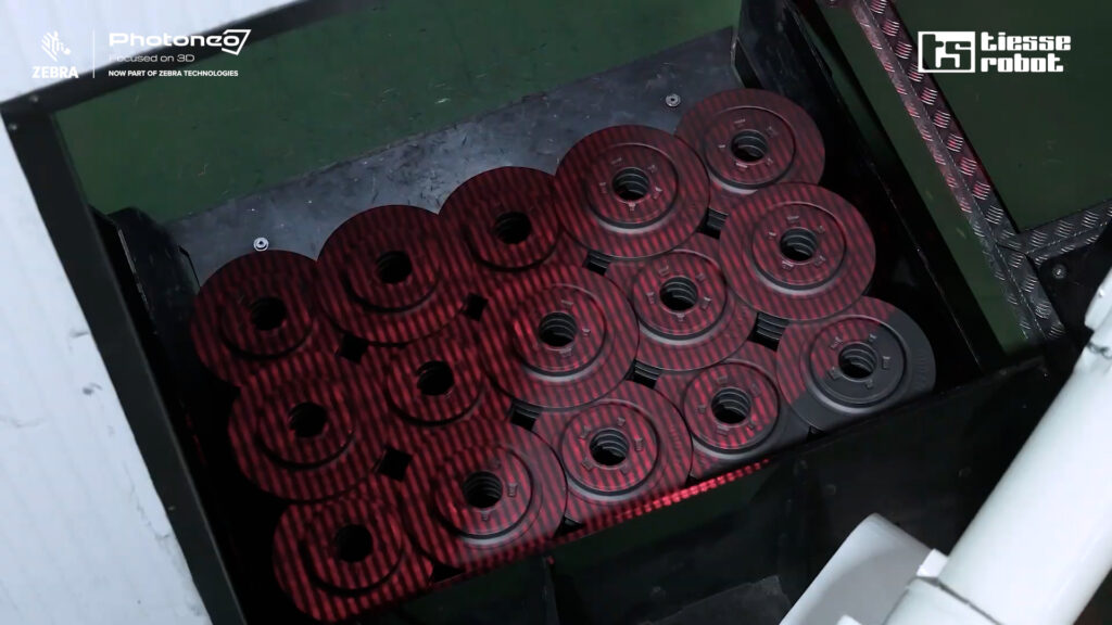 Photoneo's PhoXi 3D Scanner XL casting structured light patterns on the bin of brake discs for localization