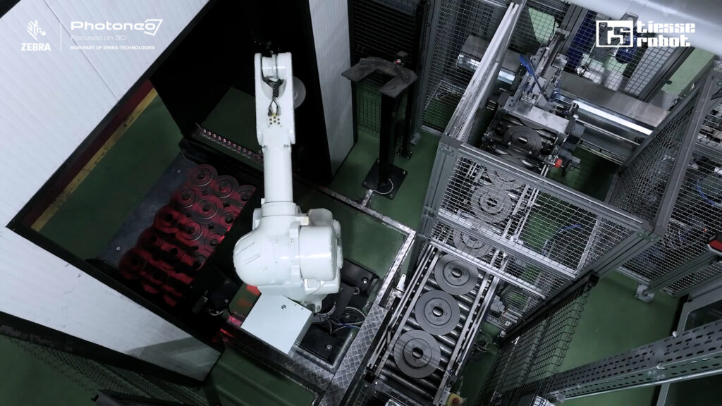 Robotic arm gripping, picking and placing brake discs from bin to rolloer conveyor belt, guided by Photoneo's PhoXi 3D Scanner and Bin Picking Studio